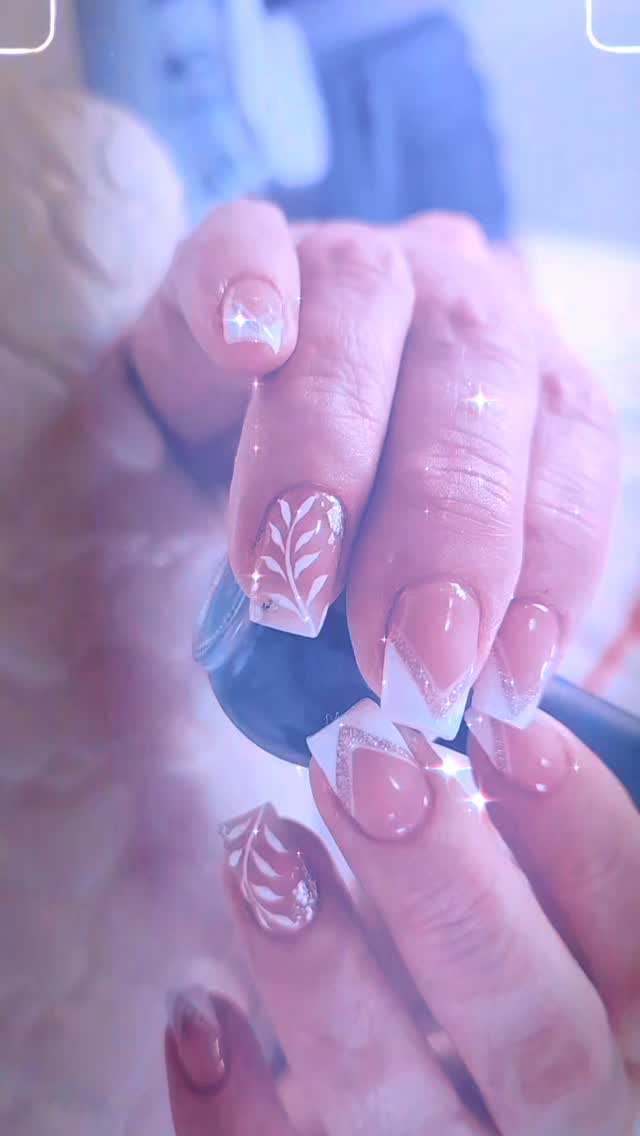 Uñas nude con diseño de hoja blanca y brillos